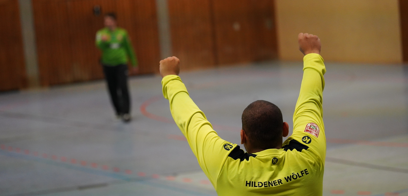 Ein Spieler in einem gr&uuml;nen Trikot hebt die Arme zum Jubel, w&auml;hrend ein weiterer Spieler im Hintergrund agiert.