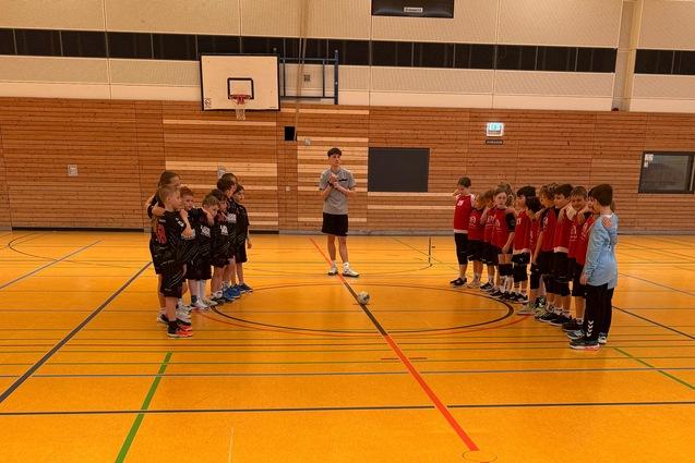 Zwei Mannschaften stehen sich auf einem Sportplatz bei einem Wettkampf gegen&uuml;ber, ein Trainer gibt Anweisungen.