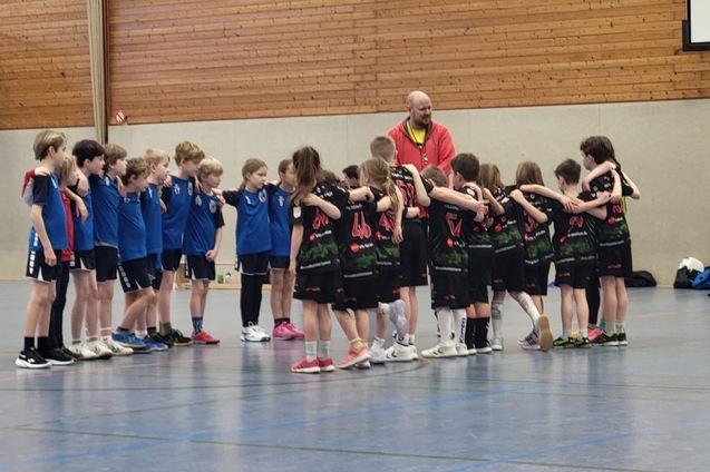 M&auml;dchenmannschaft steht in zwei Reihen, w&auml;hrend ein Trainer Anweisungen in einer Sporthalle gibt.
