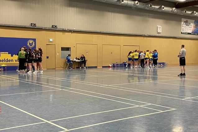 Tischtennis-Spielerinnen in Teams versammelt, w&auml;hrend ein Schiedsrichter das Spiel &uuml;berwacht. Hintergrund mit Vereinsbanner.