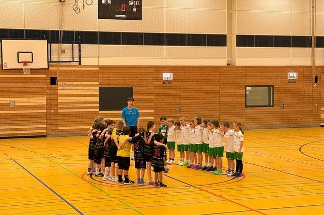 Zwei Gruppen von Jungen und M&auml;dchen stehen sich in einer Sporthalle gegen&uuml;ber und bilden einen Kreis.