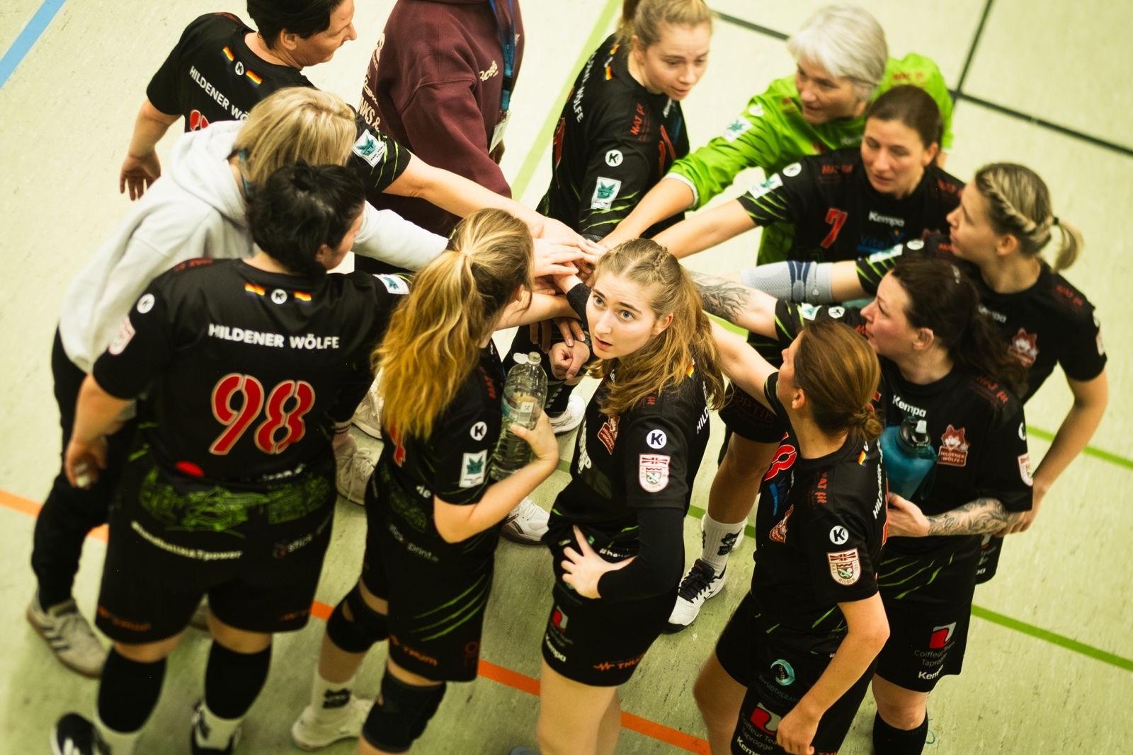 Eine Handballmannschaft bildet einen Kreis, w&auml;hrend sie sich vor dem Spiel abklatscht und motiviert.