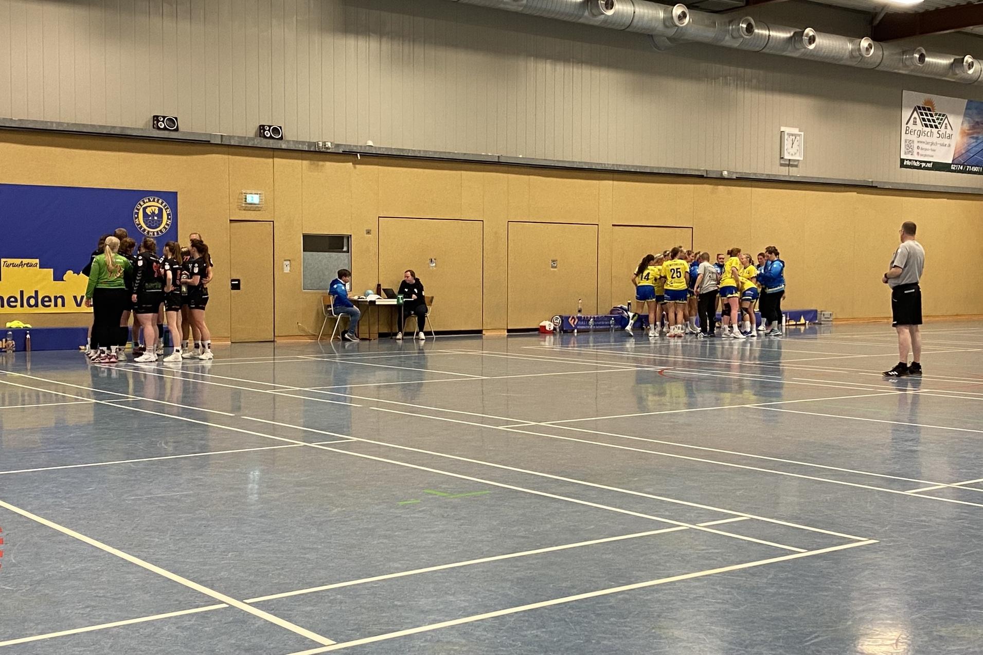 Tischtennis-Spielerinnen in Teams versammelt, während ein Schiedsrichter das Spiel überwacht. Hintergrund mit Vereinsbanner.