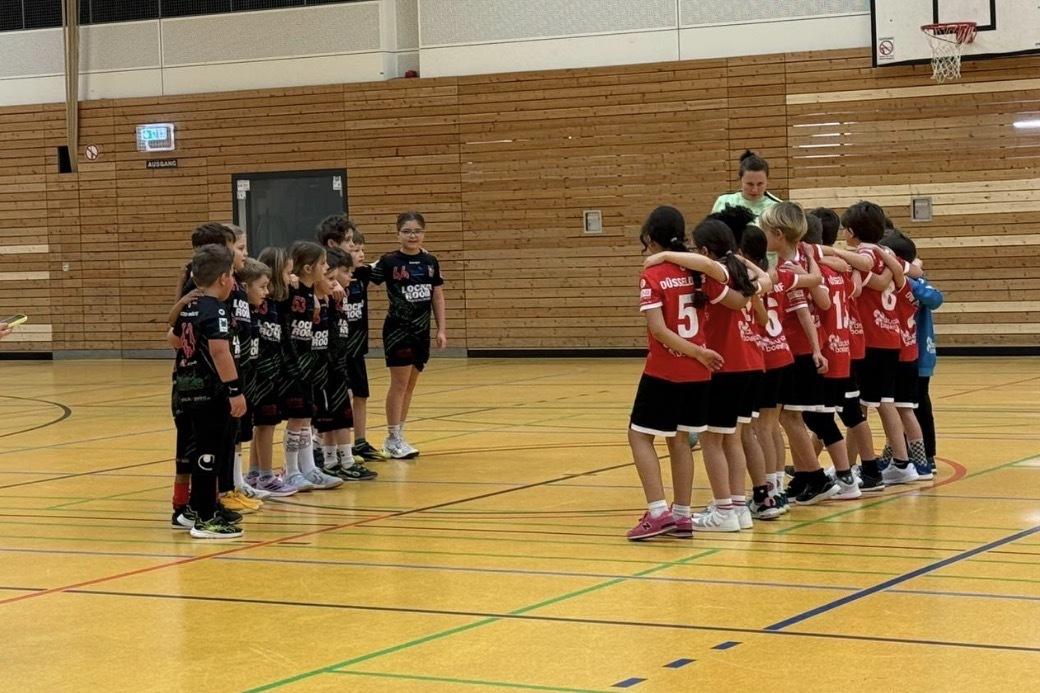 Zwei Gruppen junger Sportsler in Sportkleidung stehen sich in einer Halle gegen&uuml;ber, bereit f&uuml;r das Spiel.