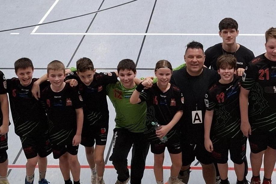 Gruppe von zwölf Jugendlichen in sportlicher Kleidung, die in einer Turnhalle für ein Gruppenfoto posieren.