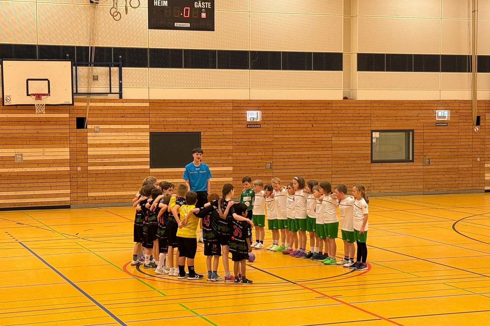 Zwei Gruppen von Jungen und Mädchen stehen sich in einer Sporthalle gegenüber und bilden einen Kreis.