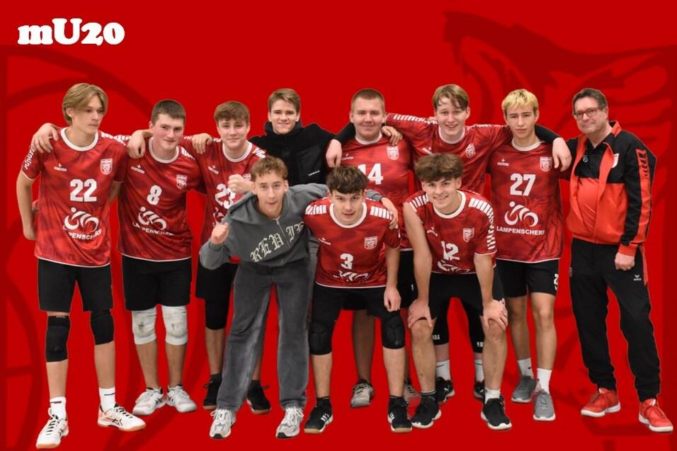 Gruppenfoto der m&auml;nnlichen U20-Handballmannschaft in roten Trikots mit Trainer vor rotem Hintergrund.