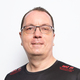 Portrait eines Mannes mit Brille in einem schwarzen T-Shirt mit dem Logo der Hildener W&ouml;lfe vor wei&szlig;em Hintergrund.