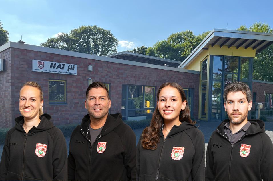 Vier Personen in schwarzen Hoodies stehen vor einem modernen Fitnessgebäude mit gelbem Eingangsbereich und Bäumen im Hintergrund.