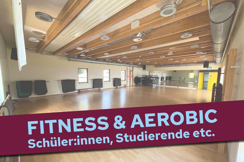 Leere Fitness- und Aerobichalle mit Holzdecke und mattierter Bodenfläche, an der Wand steht „FITNESS & AEROBIC“.