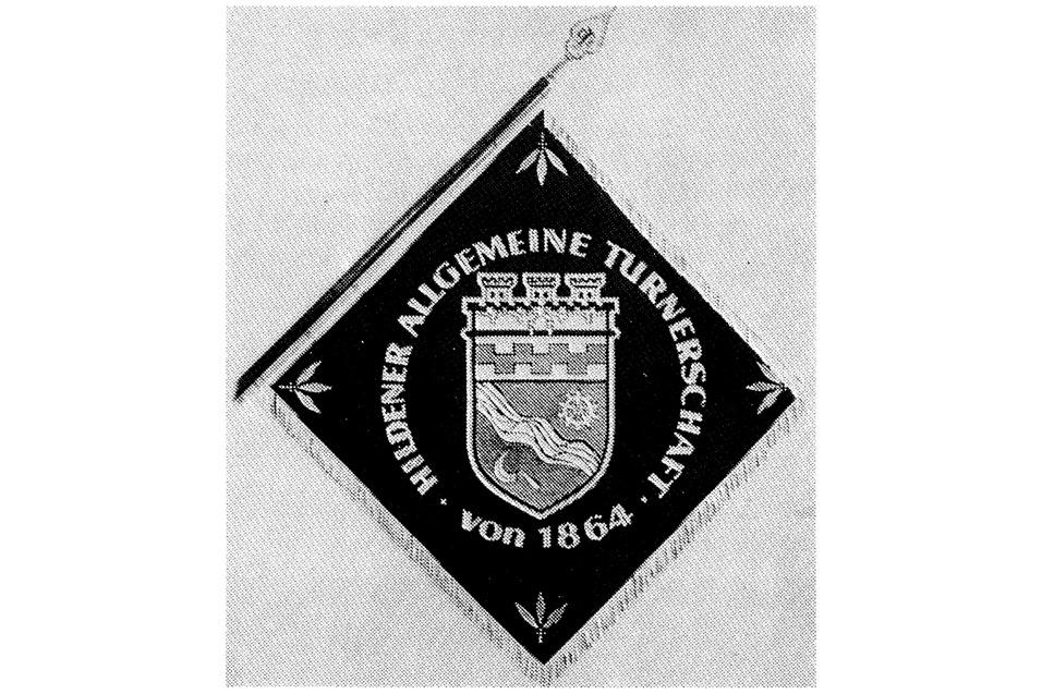 Wimpel der Hildener Allgemeinen Turnerschaft mit Wappen und Jahr 1864 auf schwarzem Hintergrund.