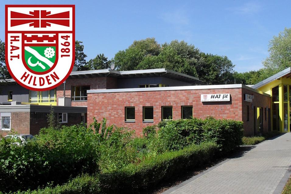 Moderne Backsteinarchitektur des HAT Hilden mit gelben Akzenten und begrüntem Umfeld an einem sonnigen Tag.