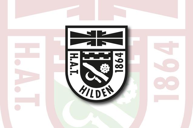 Wappen von H.A.T. Hilden 1864, schwarz-wei&szlig; mit symbolischen Elementen auf einem roten Hintergrund.