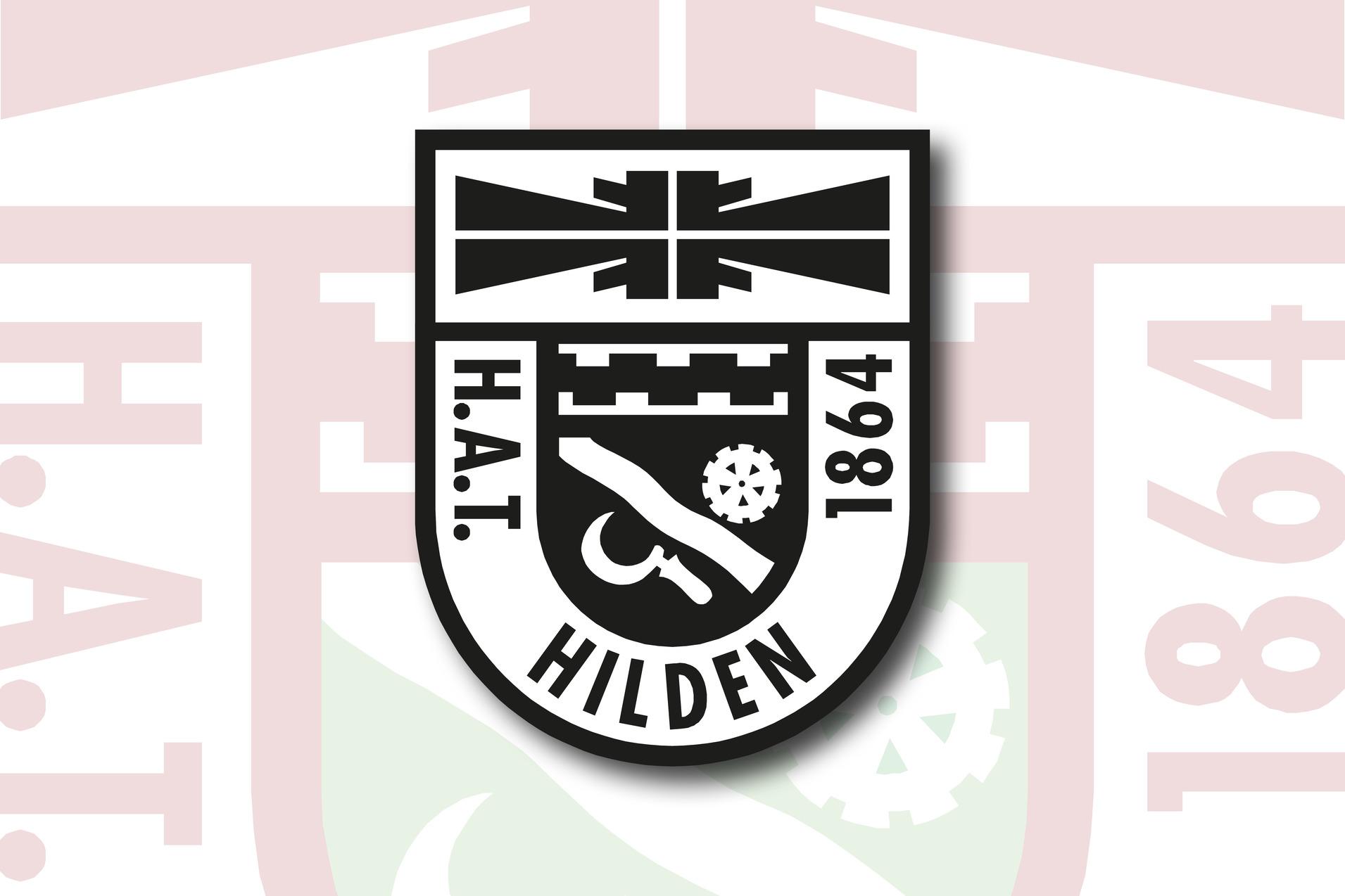 Wappen des H.A.T. Hilden mit Jahreszahl 1864 und verschiedenen Symbolen auf einem hellen Hintergrund.