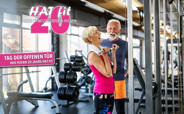 Zwei lachende Fitnessenthusiasten in einem Fitnessstudio beim Training, im Hintergrund Hanteln und Fitnessgeräte.