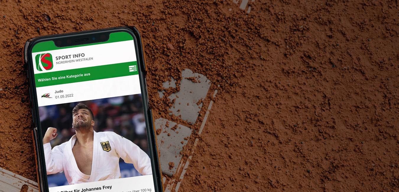 Smartphone auf rotem Tennisplatz mit Sportnachricht über Johannes Frey und EM-Silbermedaille.