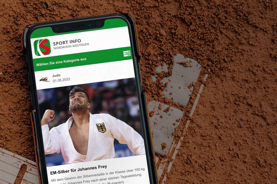 Smartphone auf rotem Tennisplatz mit Sportnachricht &uuml;ber Johannes Frey und EM-Silbermedaille.