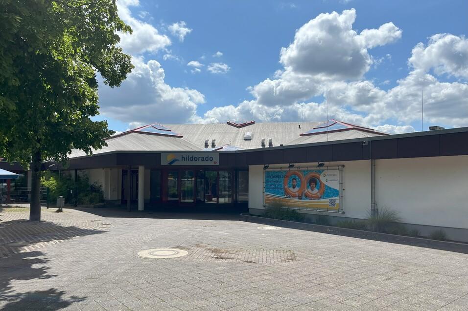Eingang des Hildorado mit Holzdach, buntem Wandbild und blauen Himmel mit Wolken im Hintergrund.