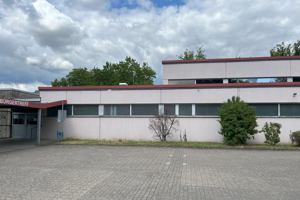 Fassade des B&uuml;rgertreffs mit Eingangsbereich und begr&uuml;nter Fl&auml;che, unter bew&ouml;lktem Himmel.