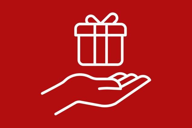 Hand, die ein Geschenk mit Schleife vor rotem Hintergrund h&auml;lt.