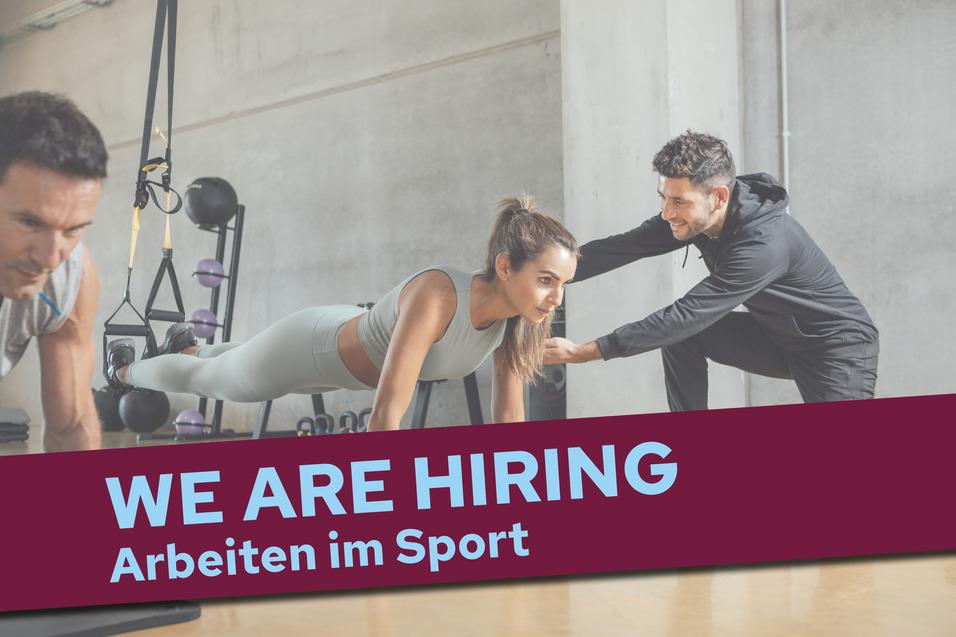 Fitness-Trainer unterstützt Frau beim Planken in einem modernen Trainingsraum, mit der Aufschrift „WE ARE HIRING – Arbeiten im Sport“.