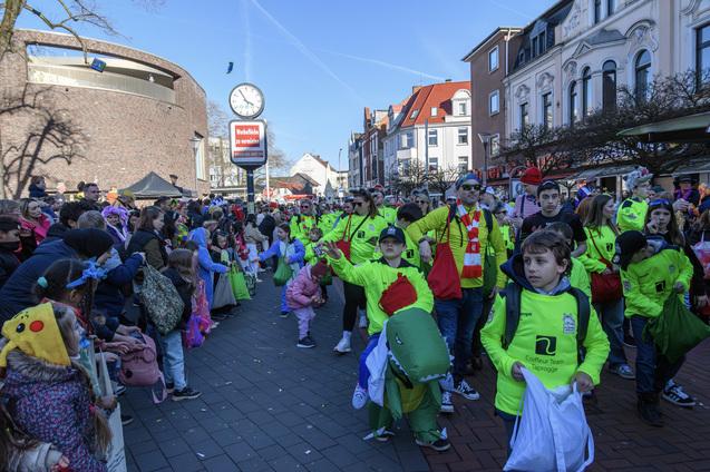 Gruppierung von Menschen in bunten Outfits auf einer belebten Stra&szlig;e w&auml;hrend einer festlichen Veranstaltung im Freien.